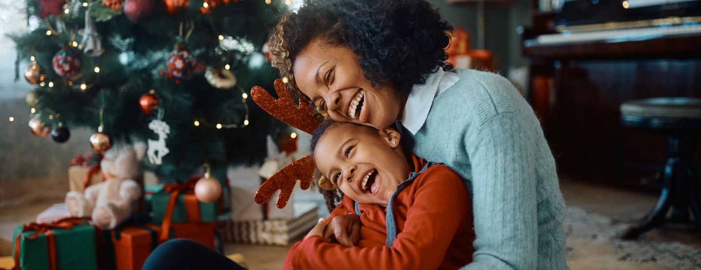 Mother and daughter laughing near the Christmas tree. 