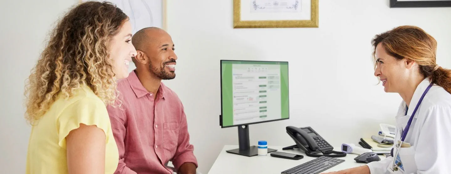 Adult couple talks with health care provider in her office.