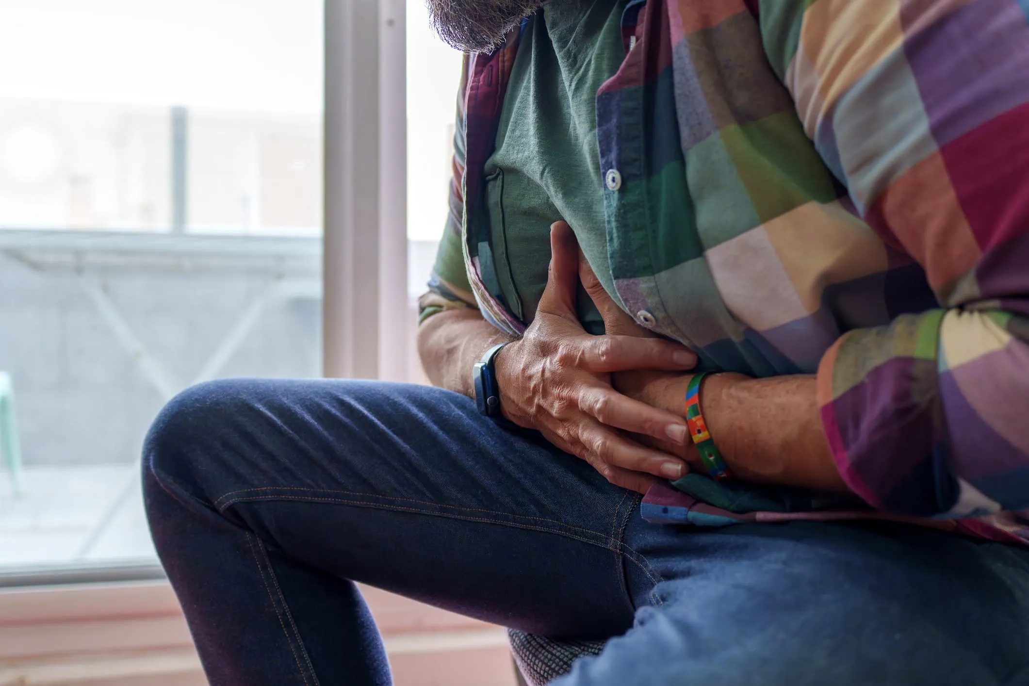 Man clutching his upper abdomen from pain