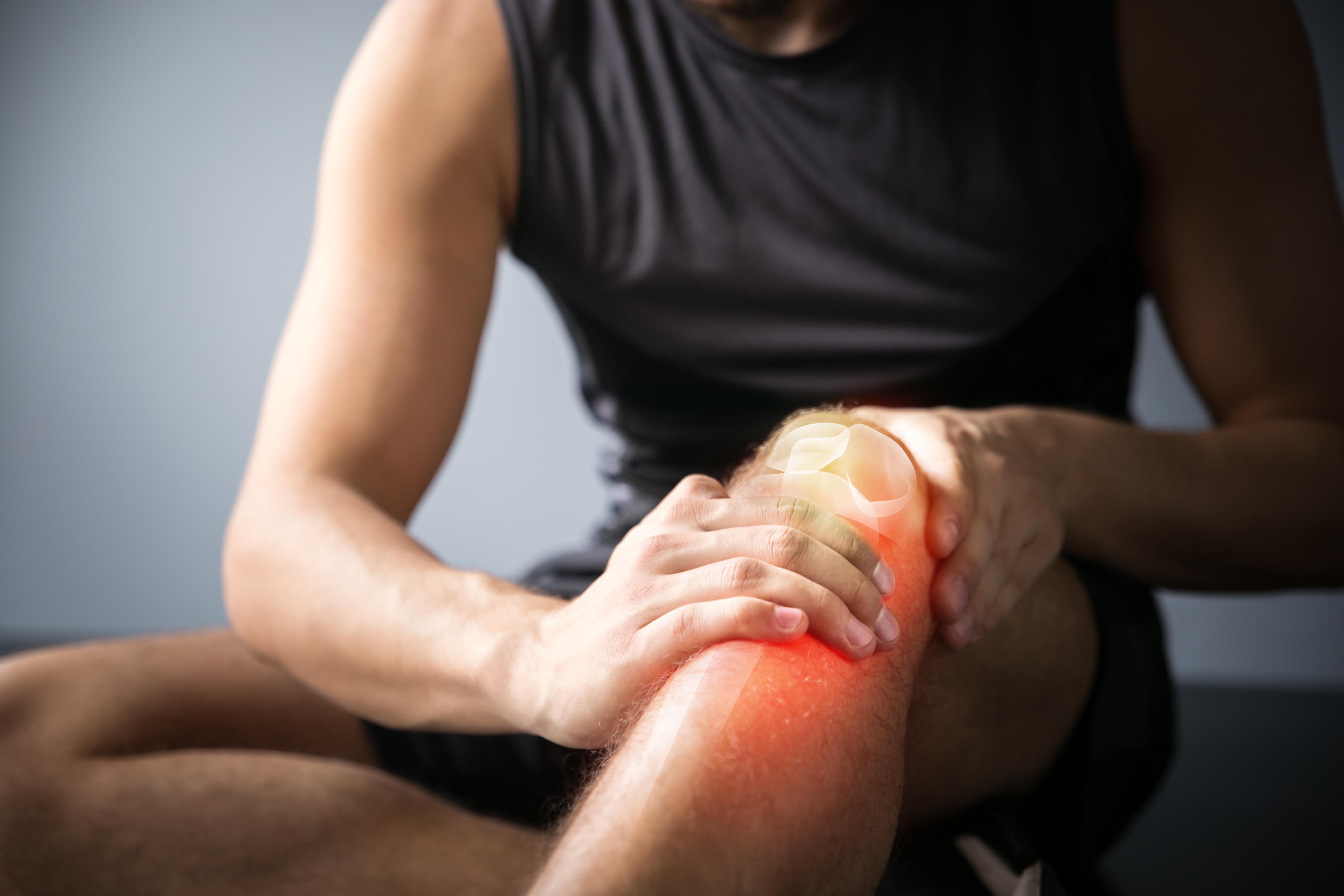 A man sitting on the ground holding his knee after an injury.