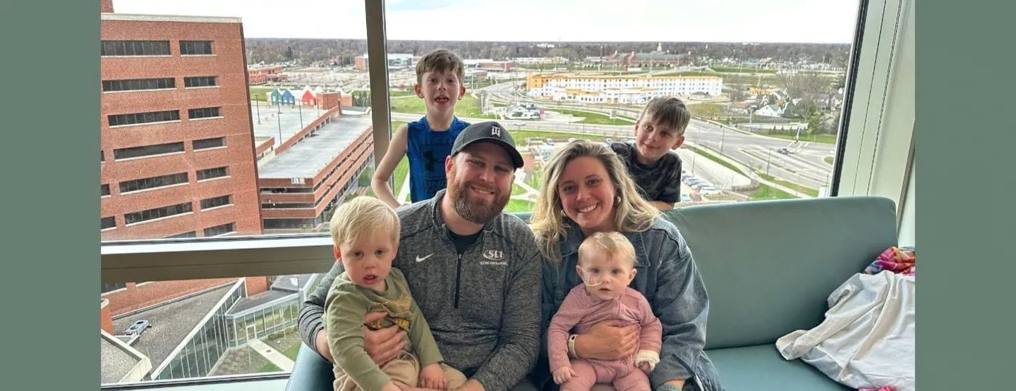The Scott family smiles in front of a large window.