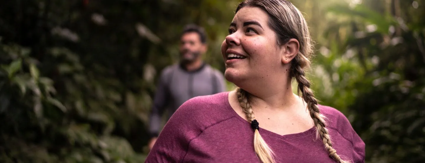 Woman smiling, walking in the trees.
