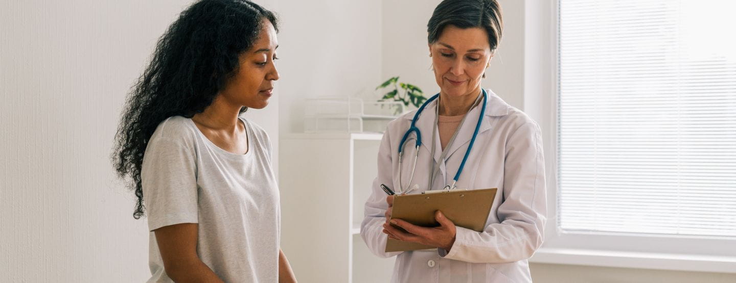 Young woman consults with physician in exam room.