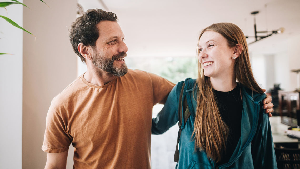 a father and his teenage daughter share a hug