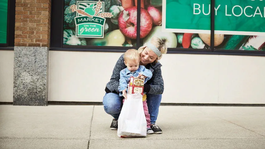 Mother squats with her child outside on the sidewalk.