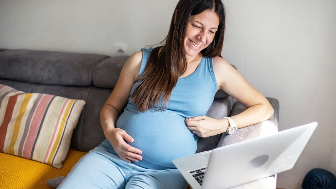 a pregnant woman views a virtual education session on her laptop
