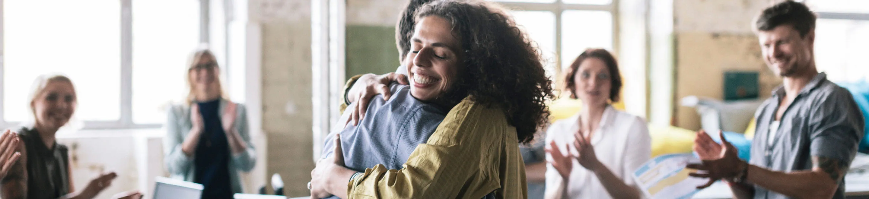 A woman is given a hug and applauded at the completion of her job training class