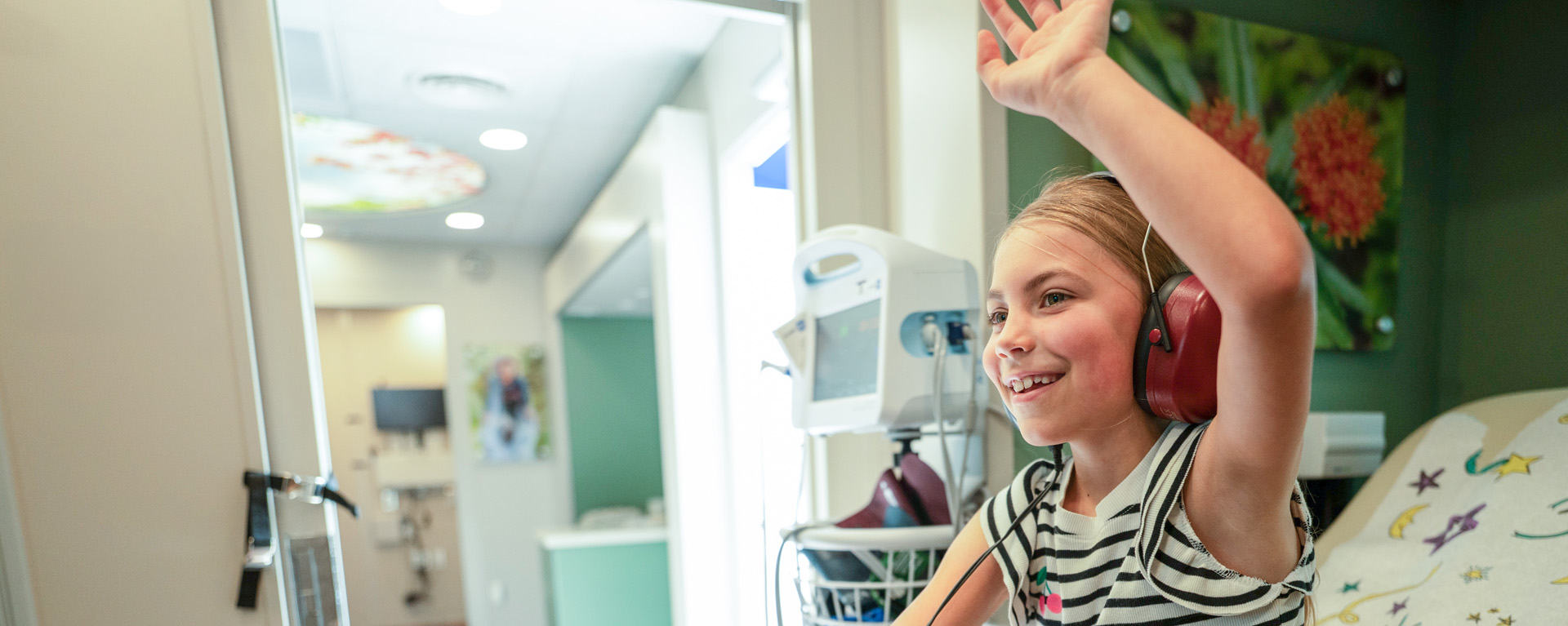 Girl getting ear test and raising hand 