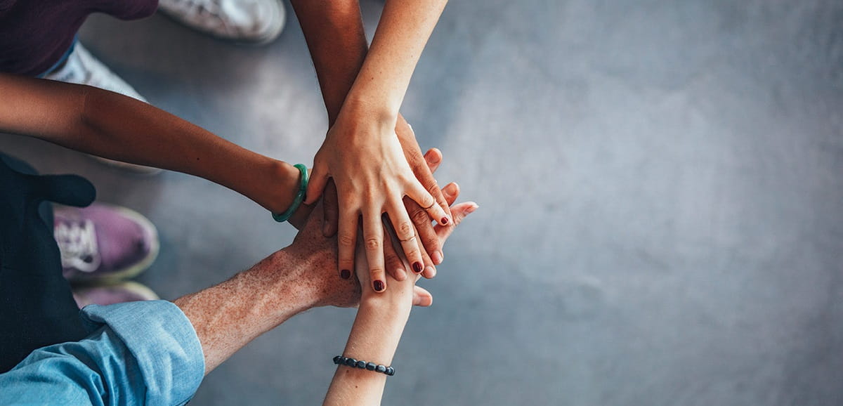 An image of five different people's hands in a pile.