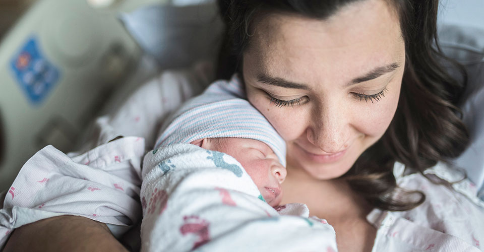 A mother hugs her newborn baby in the hospital