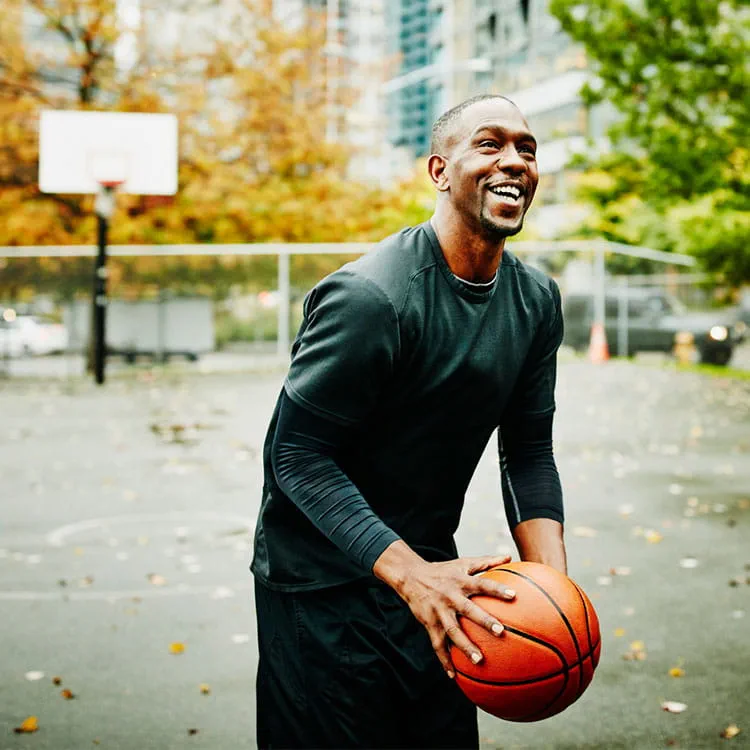 a man holds a basketball on an outdoor court