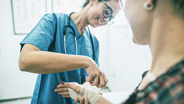A wound care nurse helps bandage a patients hand