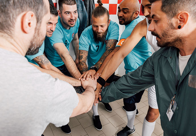 a men's soccer team comes together in a circle of hands before a game